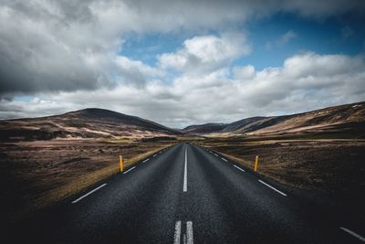 Road leading towards mountains against sky