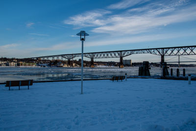 Bridge over snow covered landscape against sky