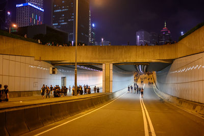 People on illuminated bridge at night