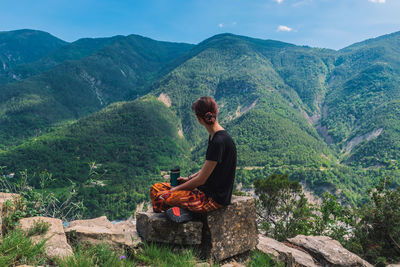 Man sitting on mountain looking at mountains