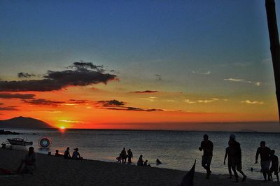 Silhouette people on beach against sky during sunset