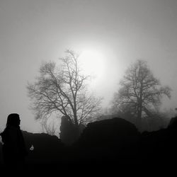 Low angle view of silhouette man sitting against clear sky