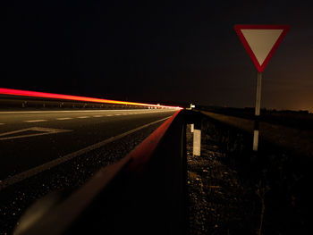 Light trails on road against sky at night