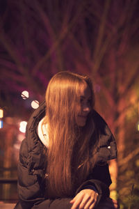 Midsection of woman looking at camera at night