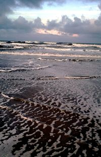 Scenic view of beach against cloudy sky