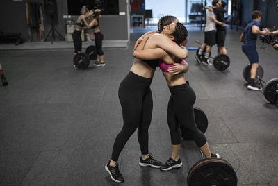 Athletes hugging each other while standing at gym