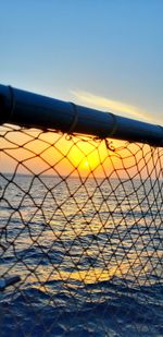 Metal fence against blue sky during sunset