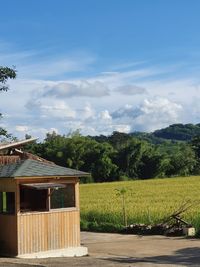 House and trees on field against sky