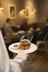 Waiter bringing scone to the table in a cafe