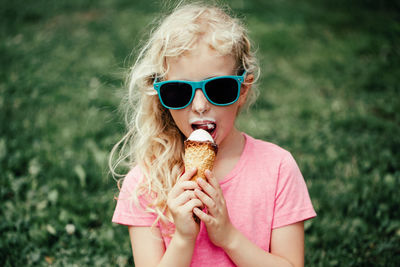 Cute funny  girl in sunglasses with dirty nose and moustaches eating ice cream from waffle cone