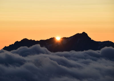 Scenic view of dramatic sky over silhouette mountains during sunset