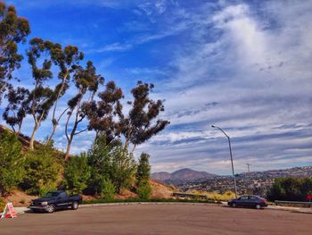 Cars on road against cloudy sky