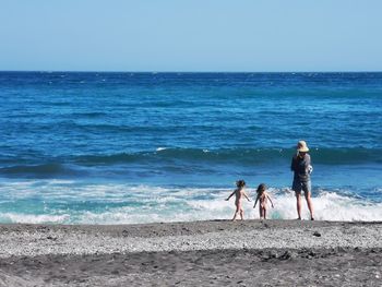 Full length of children on beach against clear sky