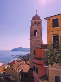 Italian village by the mediterranean sea, bell tower, cityscape, horizon, rooftops, colorful facades 