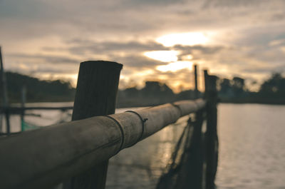 Wooden post in sea against sky during sunset