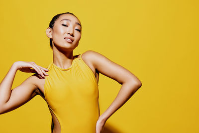 Portrait of young woman against yellow background