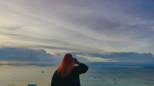 Rear view of woman looking at sea at sunset