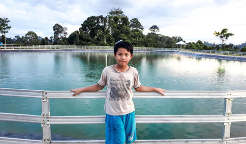 Portrait of man standing by railing against lake