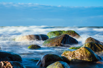 Scenic view of rocks in sea against sky