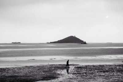 Rear view of silhouette man standing on beach against sky