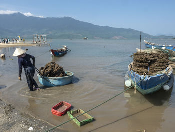 Fishing boats moored on sea against sky