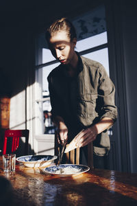 Mid adult man standing by table at home