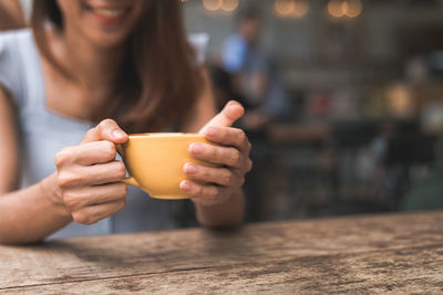 Midsection of woman holding coffee cup in cafe