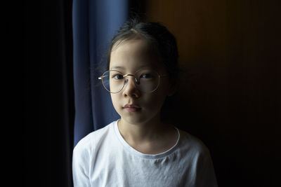 Portrait of young woman standing against wall