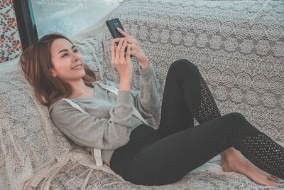 Midsection of woman using mobile phone while sitting outdoors