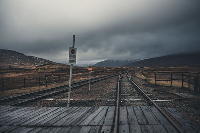 Railroad tracks leading towards mountain against sky