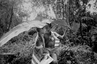 Boy with brother holding leaf during rainy season