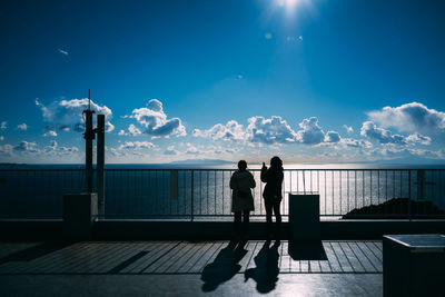 Rear view of silhouette people standing against sea