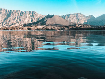 Swimming pool by lake against mountain range