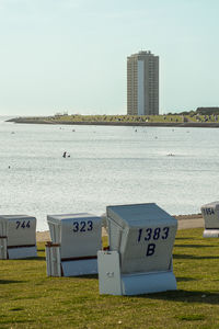 Hooded beach chairs by sea against sky in city