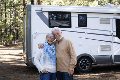 Happy senior couple standing in front of motor home