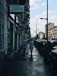 Rear view of man walking on street in rainy season