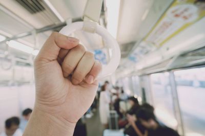 Cropped hand holding handle in bus