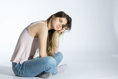 Smiling young woman sitting against white background