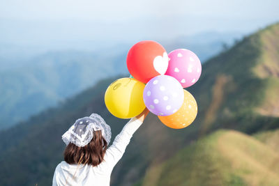 Rear view of woman holding balloons