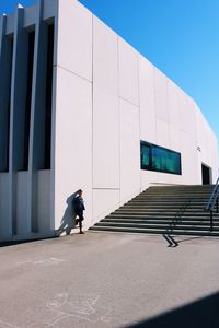 Woman standing by building against clear sky