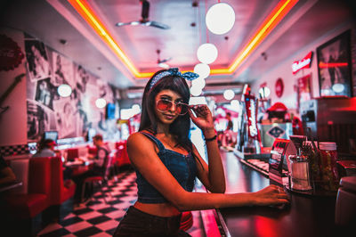 Young woman wearing eyeglasses sitting in nightclub