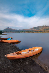 Boats moored on lake against sky