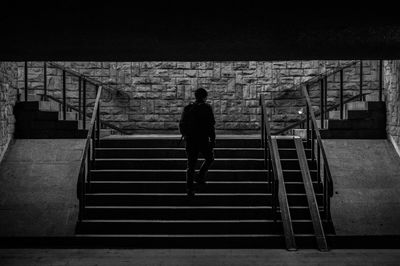 Rear view of man walking on staircase