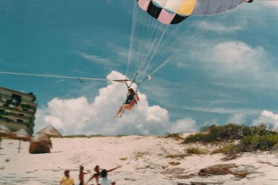 Low angle view of man paragliding over sea against sky