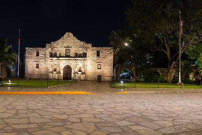 Illuminated building by street at night