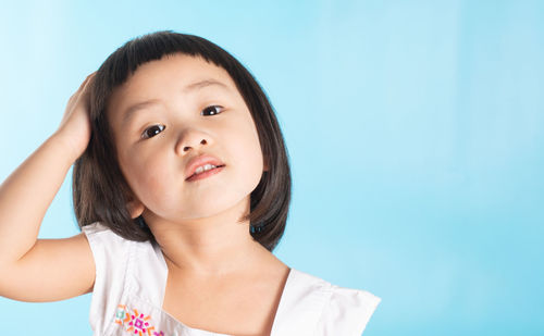 Portrait of a girl looking away against blue background