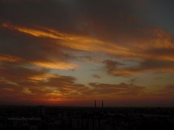 Silhouette buildings against dramatic sky during sunset