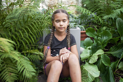 Portrait of young woman sitting against plants