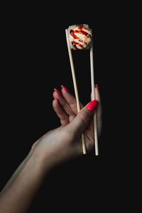 Close-up of hand holding ice cream against black background
