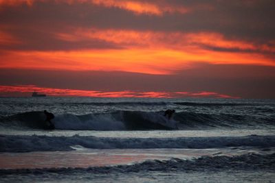 Scenic view of beach against cloudy sky during sunset